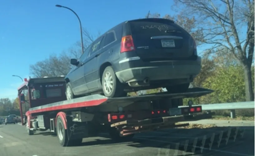 Flatbed tow truck loades with a red car in Minneapolis mn
